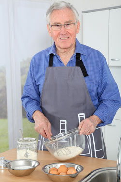 Elderly man whisking eggs in the kitchen