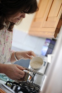 woman pouring a cup of rice into a pan