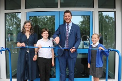 Cllr Alex Dale cuts the ribbon assisted by headteacher Katie Forster and head pupils