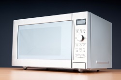 silver microwave sitting on a wooden table