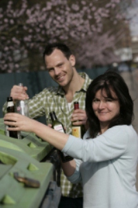 couple putting glass bottles into a bottle bank