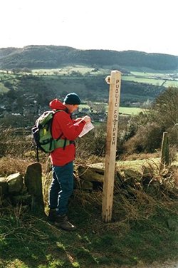 Countryside walker by a signpost checking a map