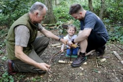 two men with a young girl starting a fire in the woods countryside events 2022