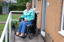 woman in wheelchair using a ramp outside her home