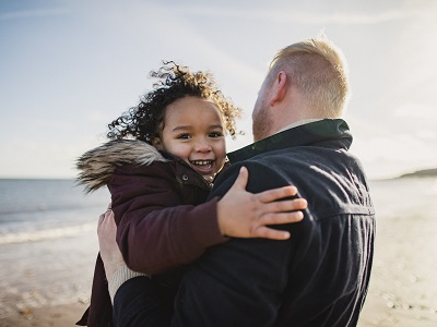 Dad carrying his daughter on the beach