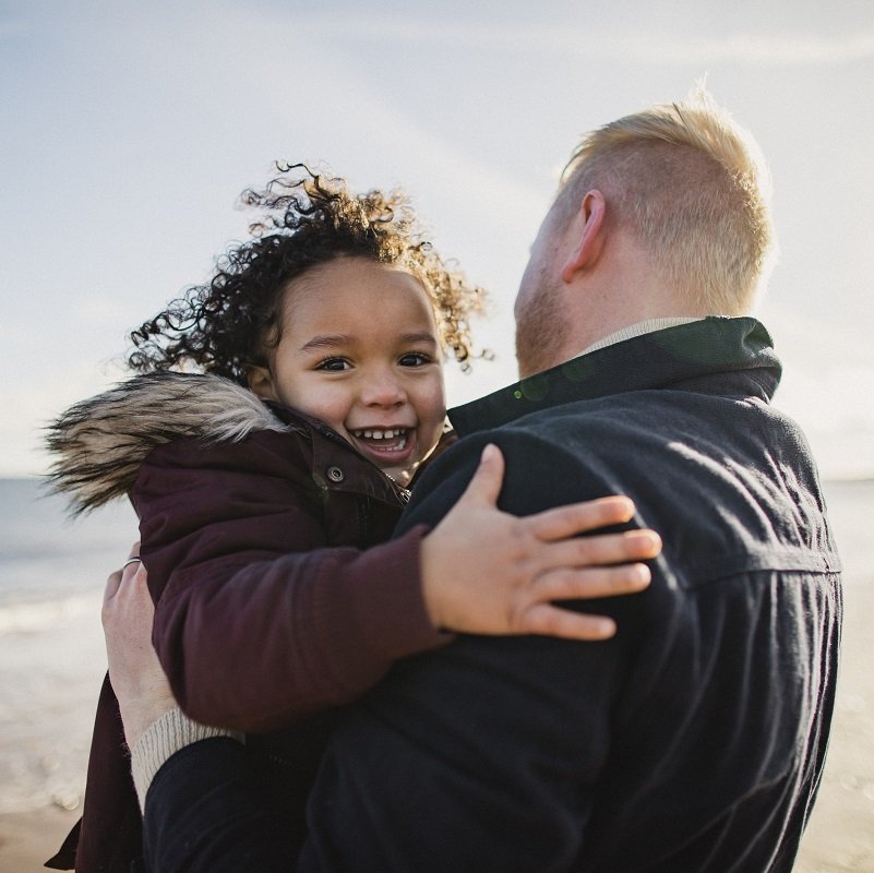 Dad carrying his daughter on the beach