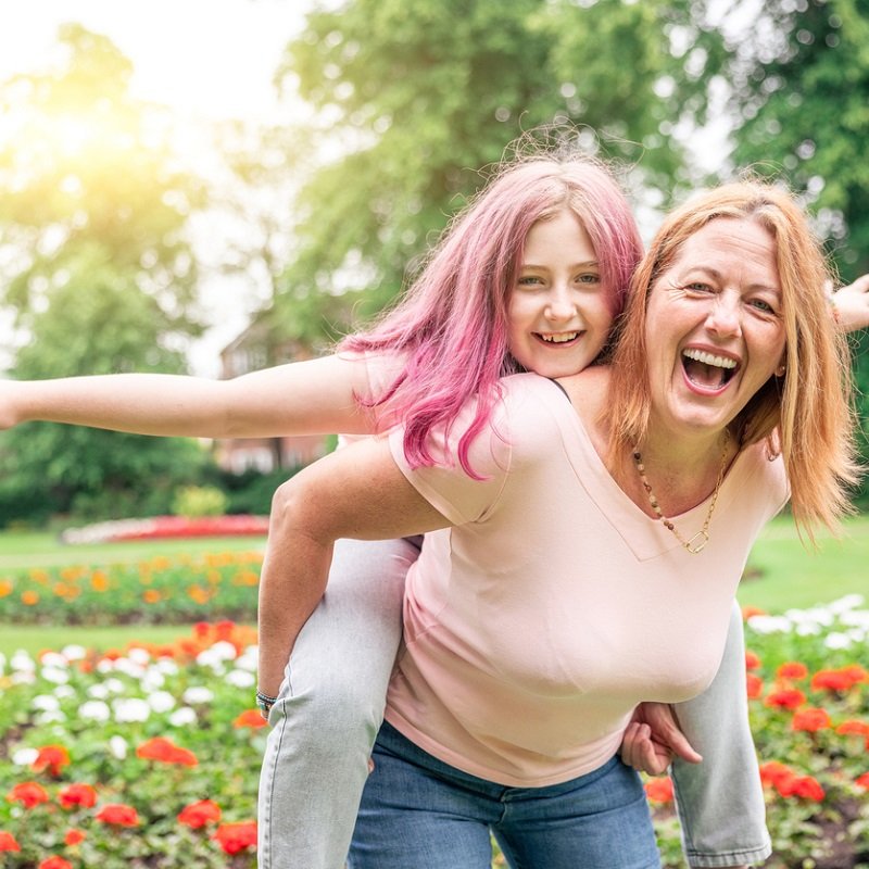 Mum giving her daughter a piggy back