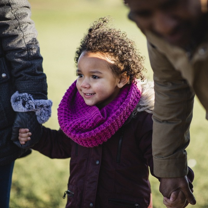 Young girl holding parents hands